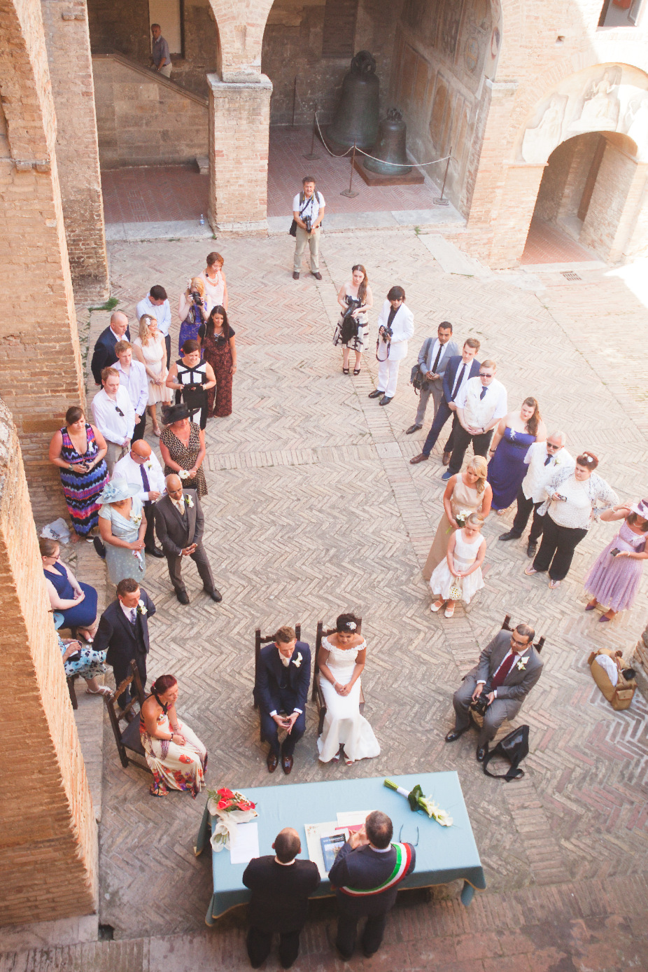 Wedding guests gather in a historic brick courtyard during an outdoor reception celebration.