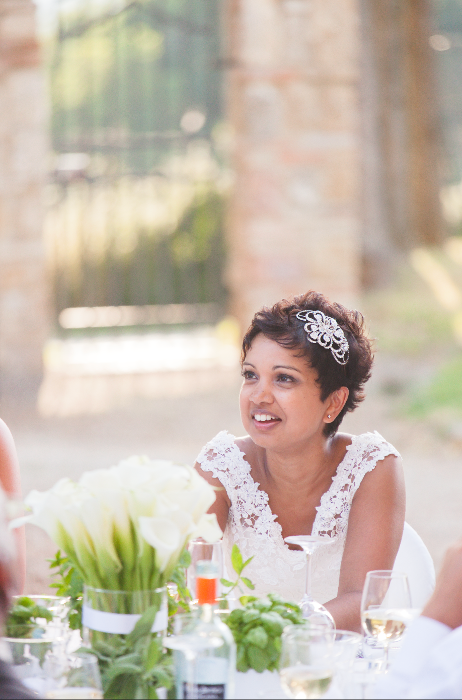 Candid moment of bride smiling at outdoor wedding reception with table decorations.