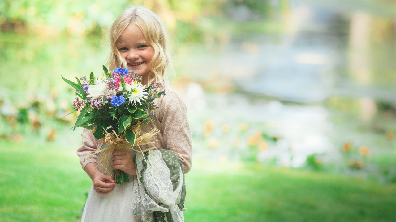 Bridemaid at the water's edge smiling with a boquet at a wedding in Somerset.