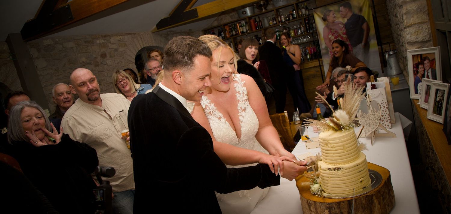 Wedding couple cutting their traditional white tiered cake at the reception.