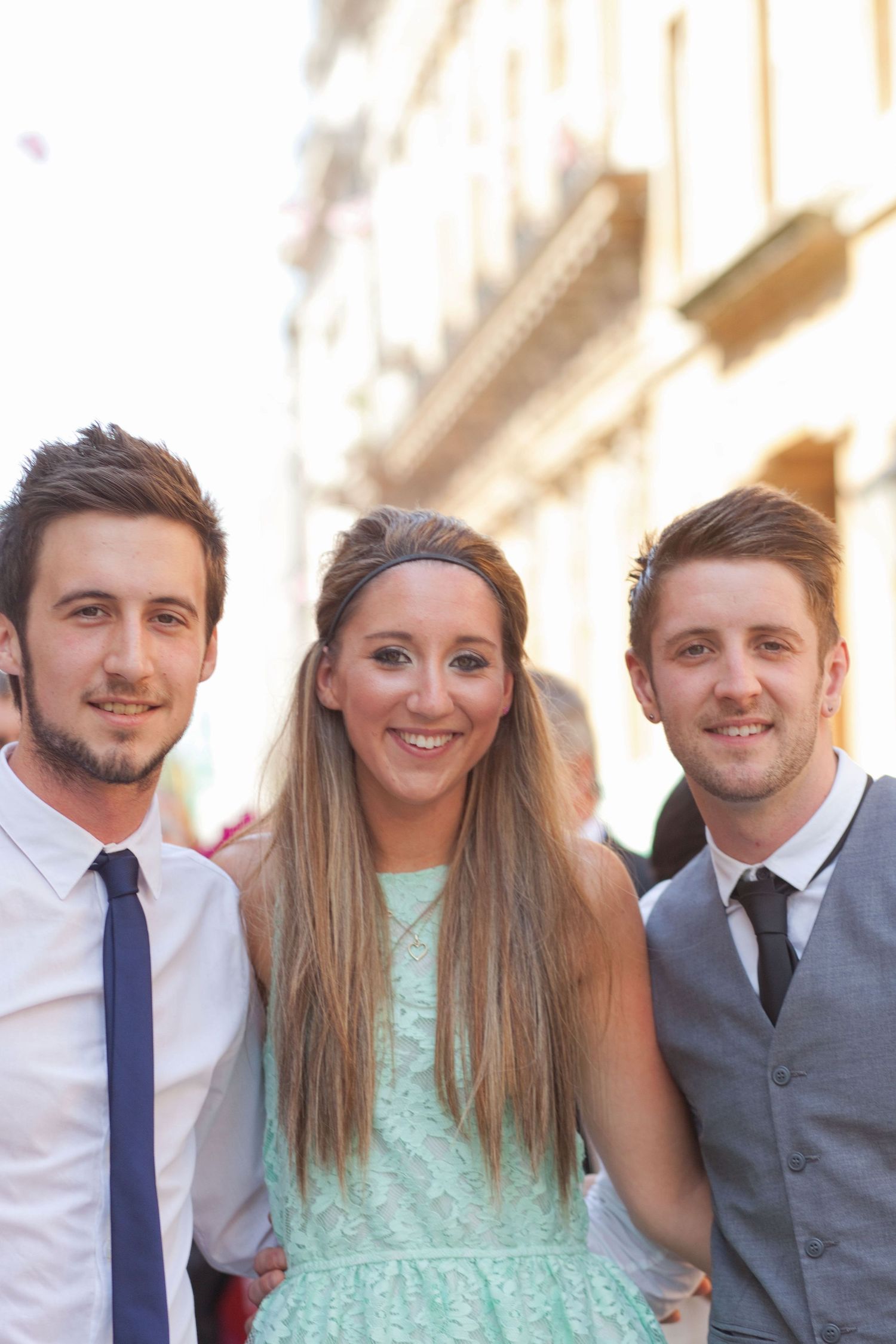Wedding party members in mint dress and dark suits smile for casual group photo.