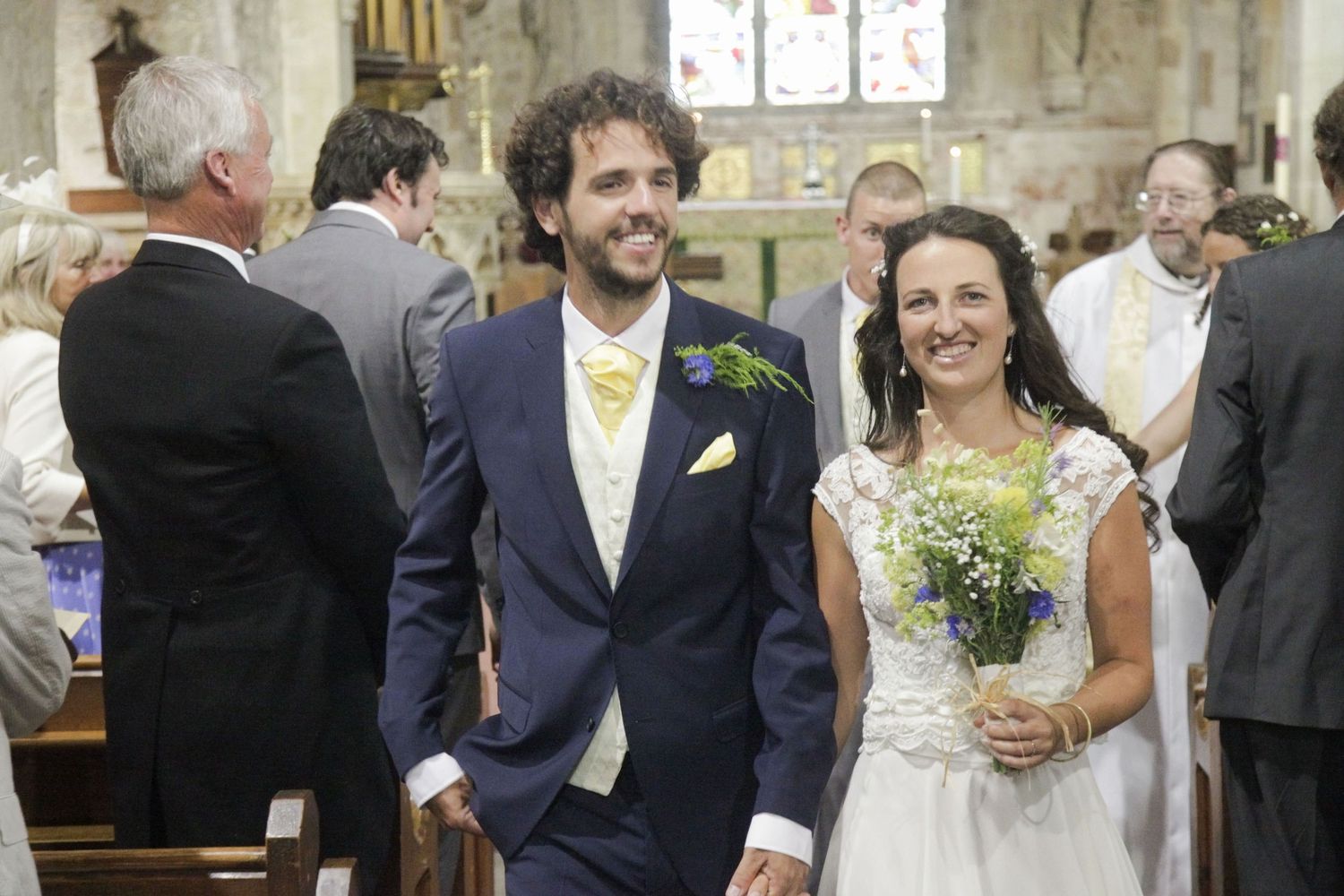 Wedding celebration inside stone church with natural light streaming through windows.