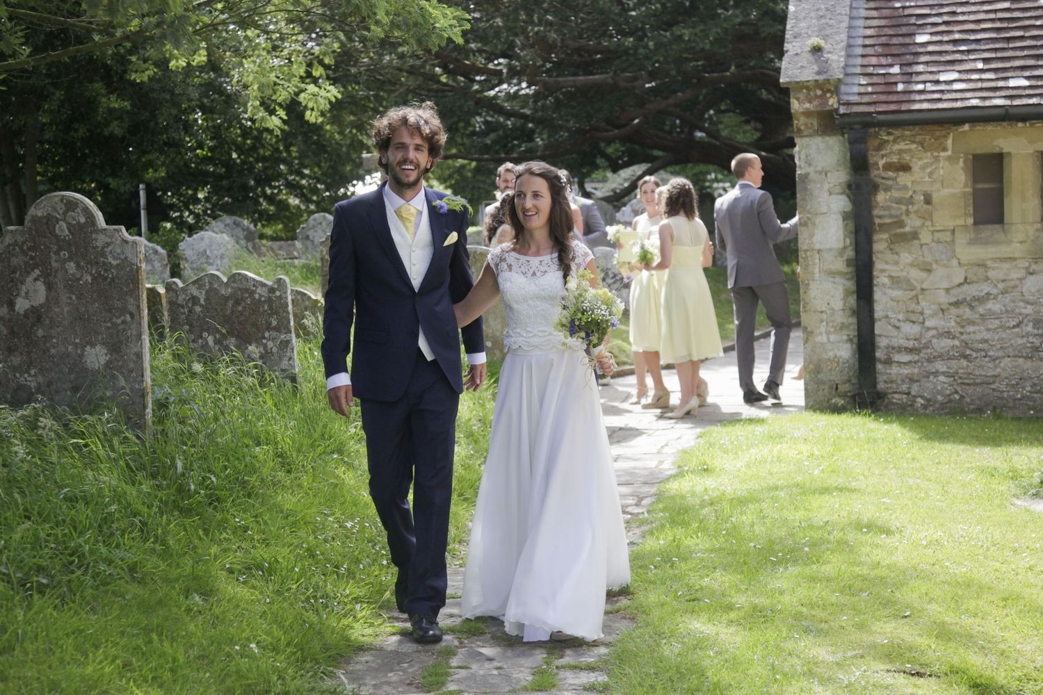A couple strolls through a rustic church garden on their wedding day.