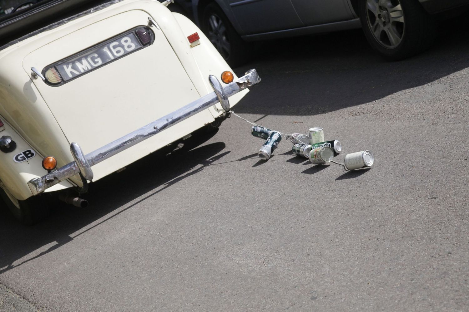Close-up view of vintage cream-colored car's rear section with wedding decorations.