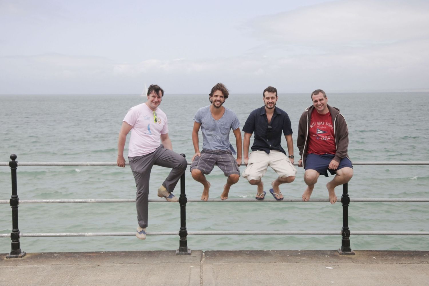 Group sitting casually on a seaside railing with ocean view in the background.
