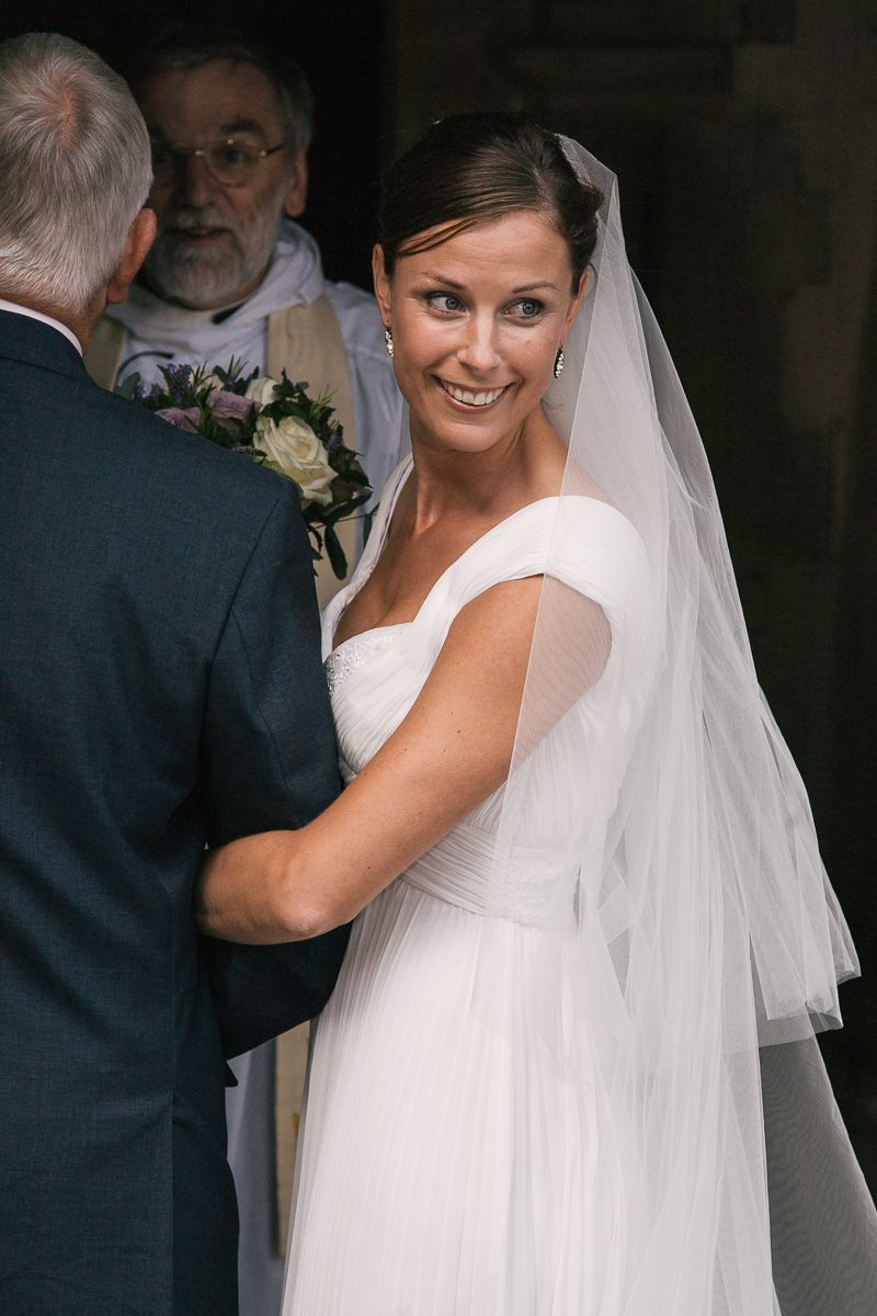 Elegant bride wearing a flowing white dress and veil at an indoor venue.