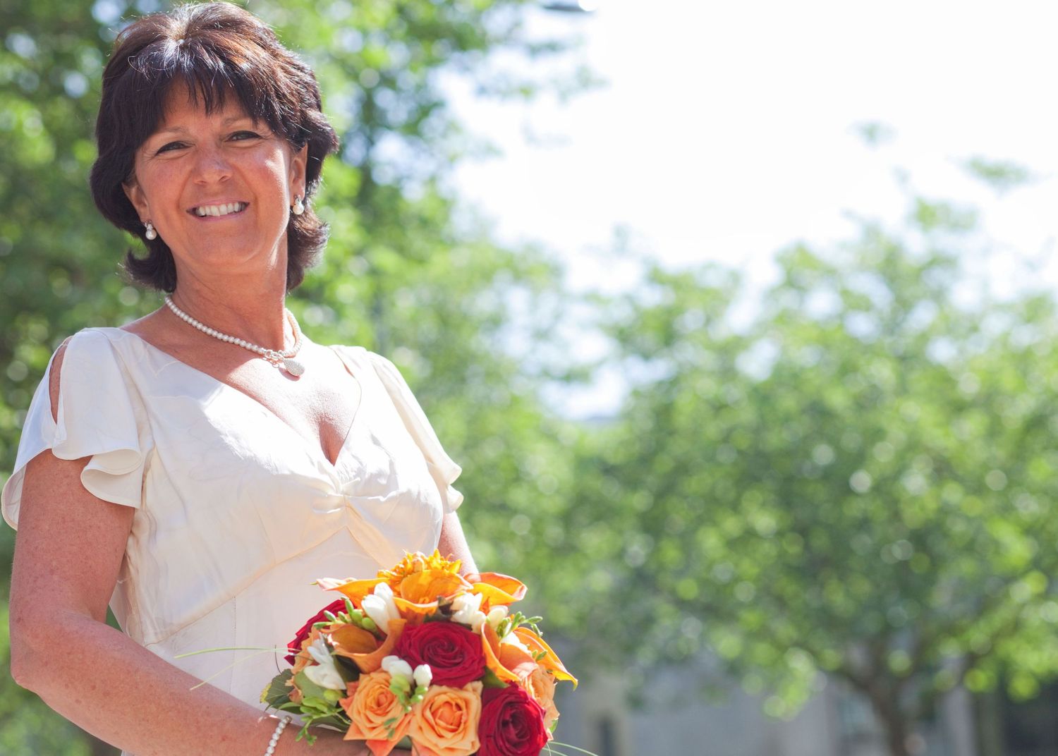Wedding party members in white and red attire posing with bouquets in an outdoor garden setting.