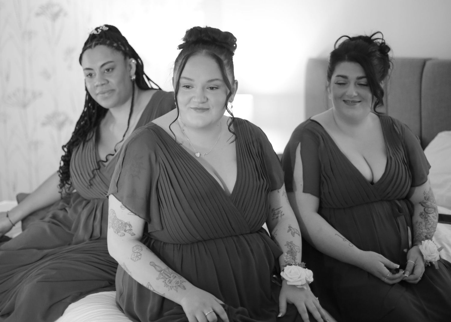 Group of women in matching gray dresses sit together during wedding preparations.