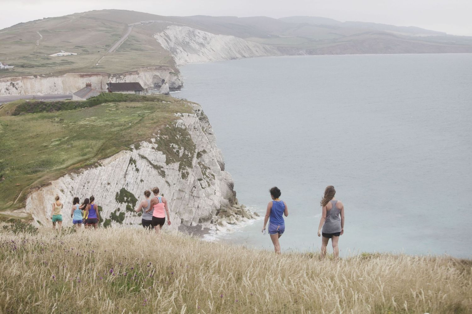 Scenic coastal landscape with white cliffs and blue water under cloudy skies.