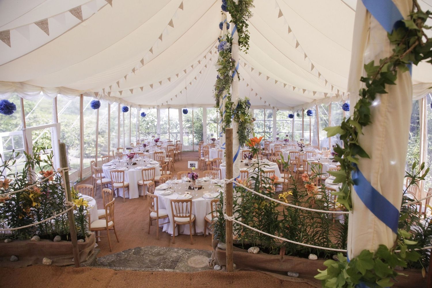 Wedding reception tent interior decorated with bunting and greenery.