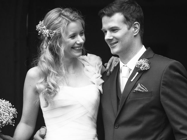 A black and white wedding photo showing a couple sharing a joyful moment outside.