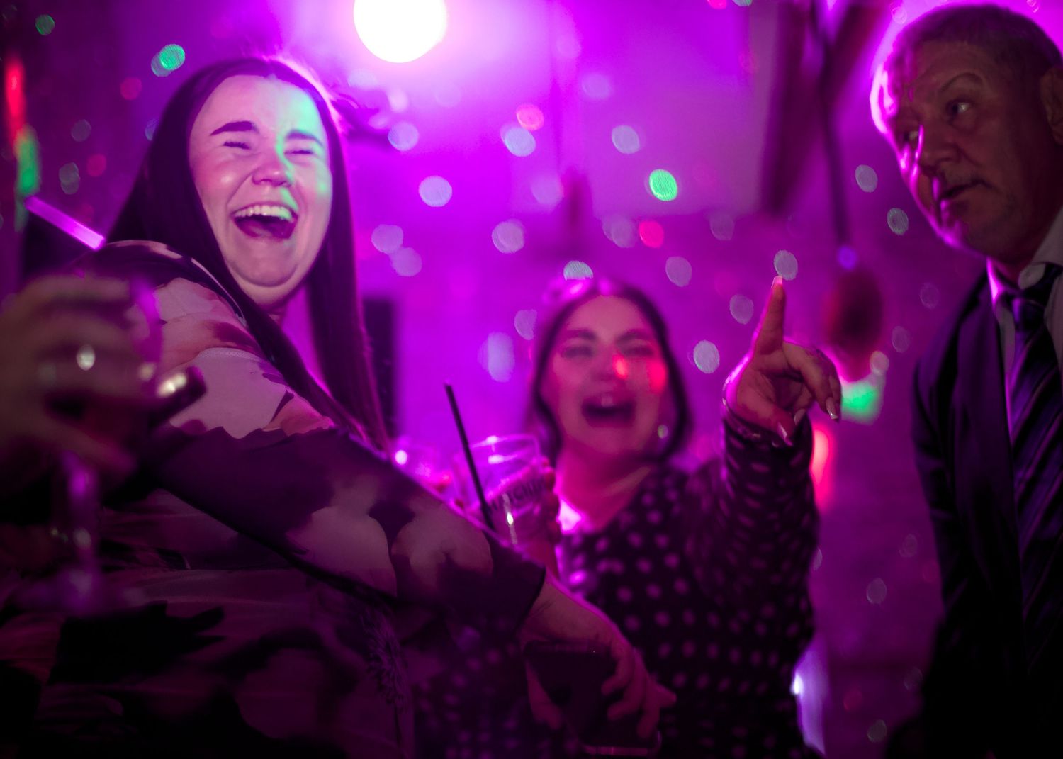 Crowd enjoying a concert under purple and pink lighting effects.
