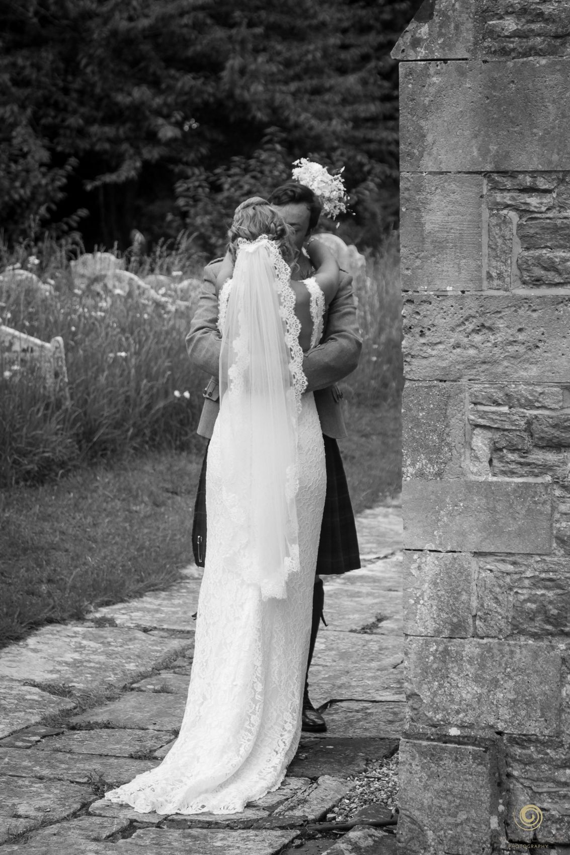 Black and white wedding photos captured at rustic stone church entrance.
