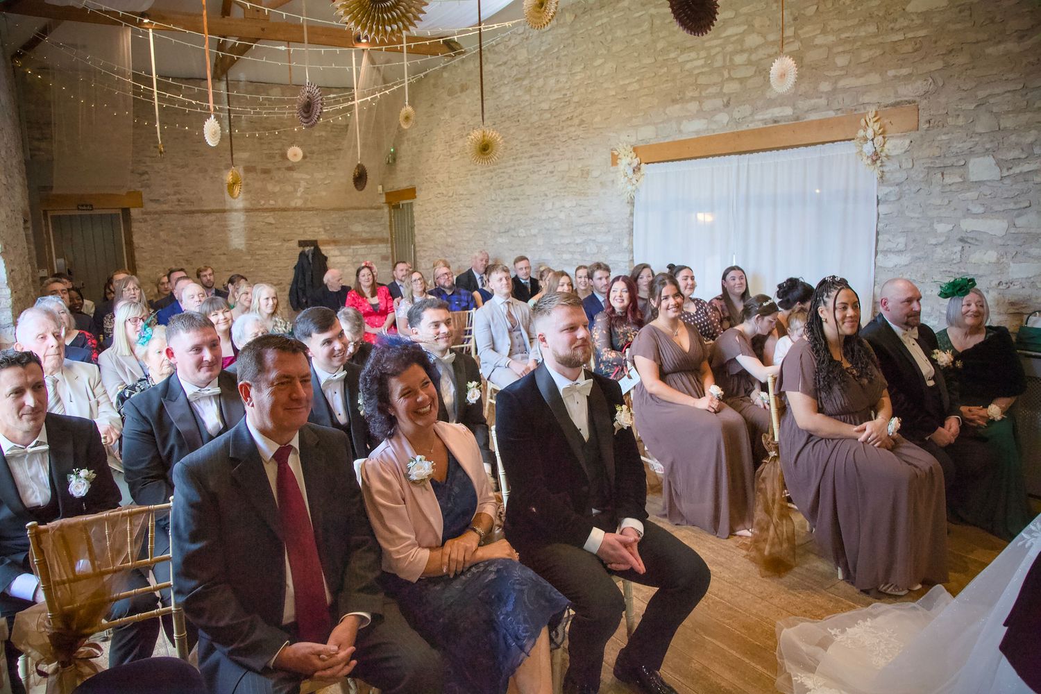 Wide angle view of wedding guests seated in a rustic brick venue with hanging lights.