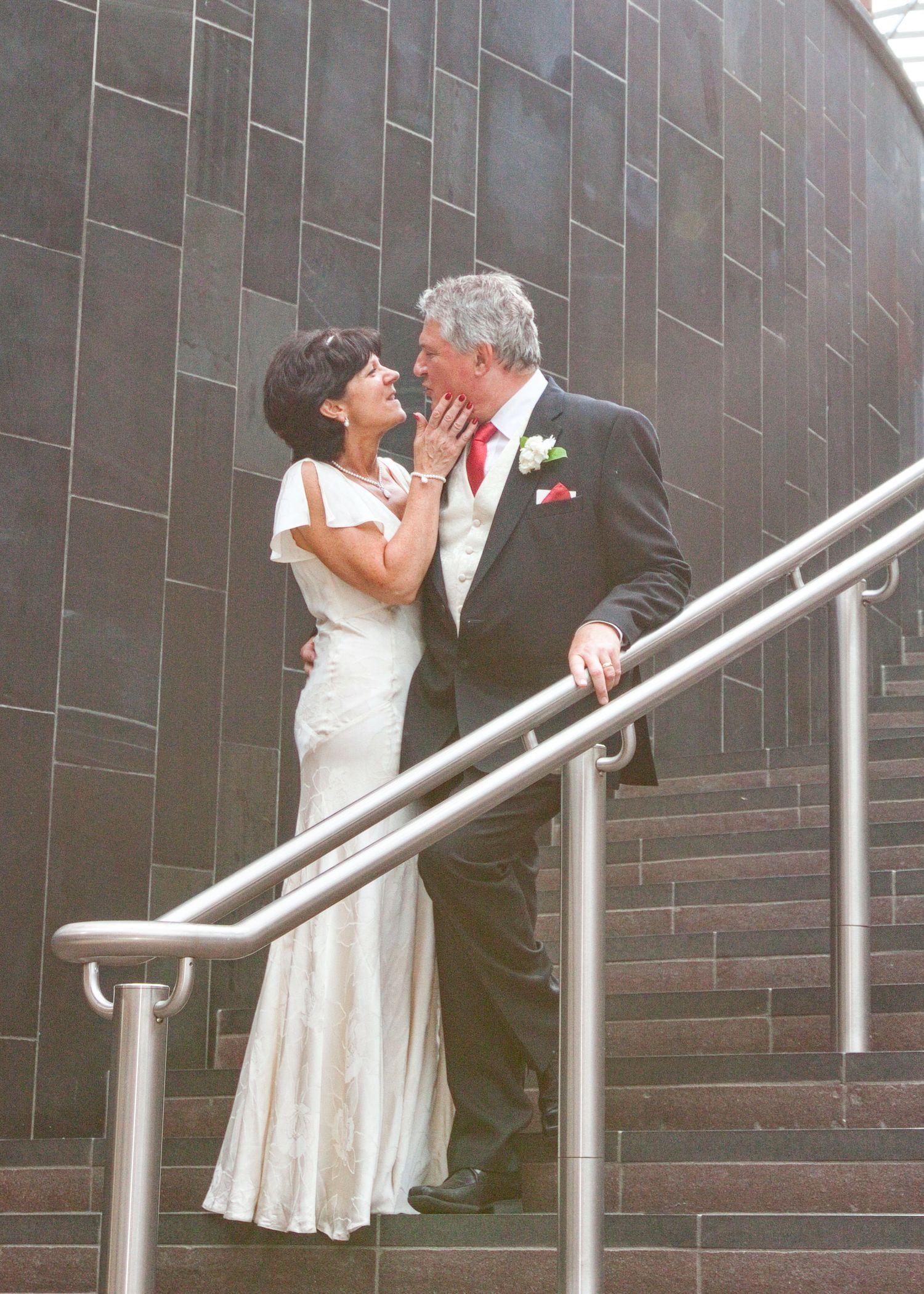 Wedding couple shares intimate moments on modern staircase in sequence of photos.