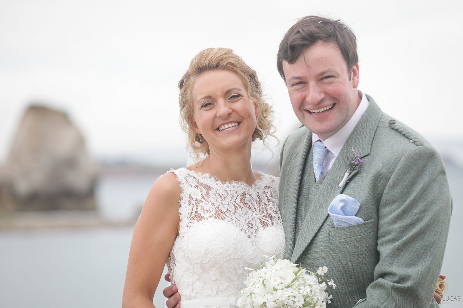 Joyful wedding portraits taken on a bright day with ocean views in the background.