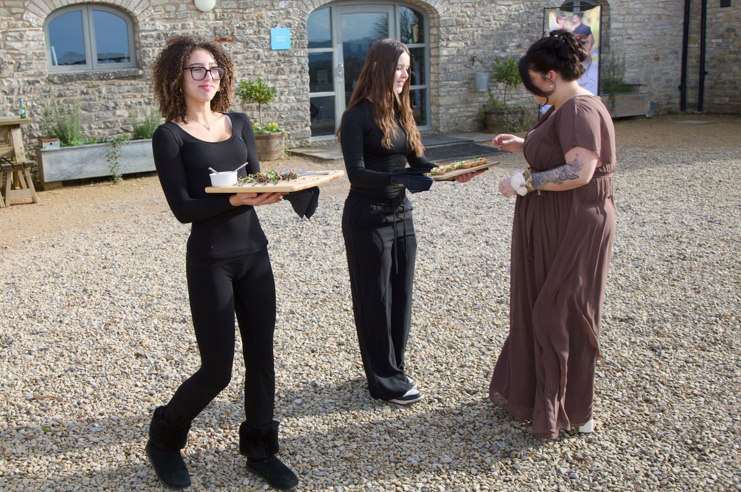Wedding ceremony preparations taking place in rustic stone courtyard with guests mingling.