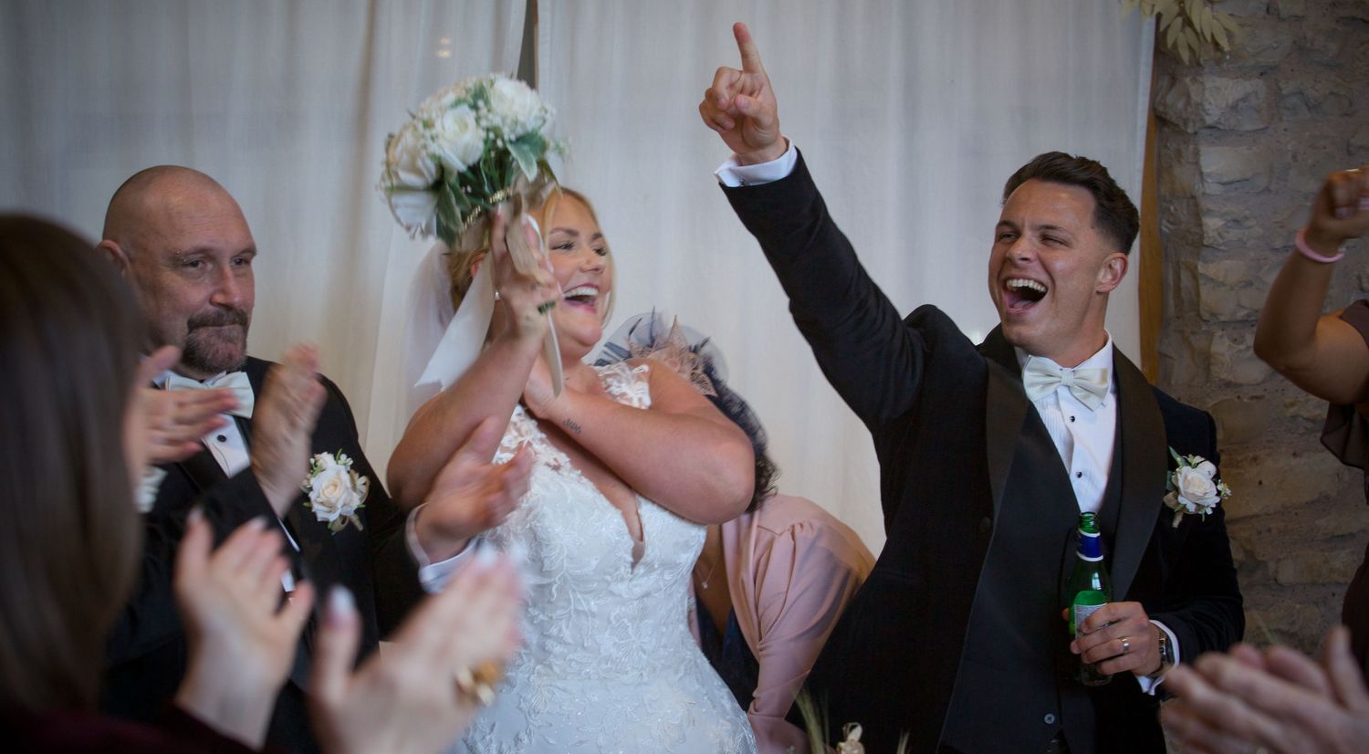 Wedding celebration with guests dancing and enjoying festivities in rustic venue.