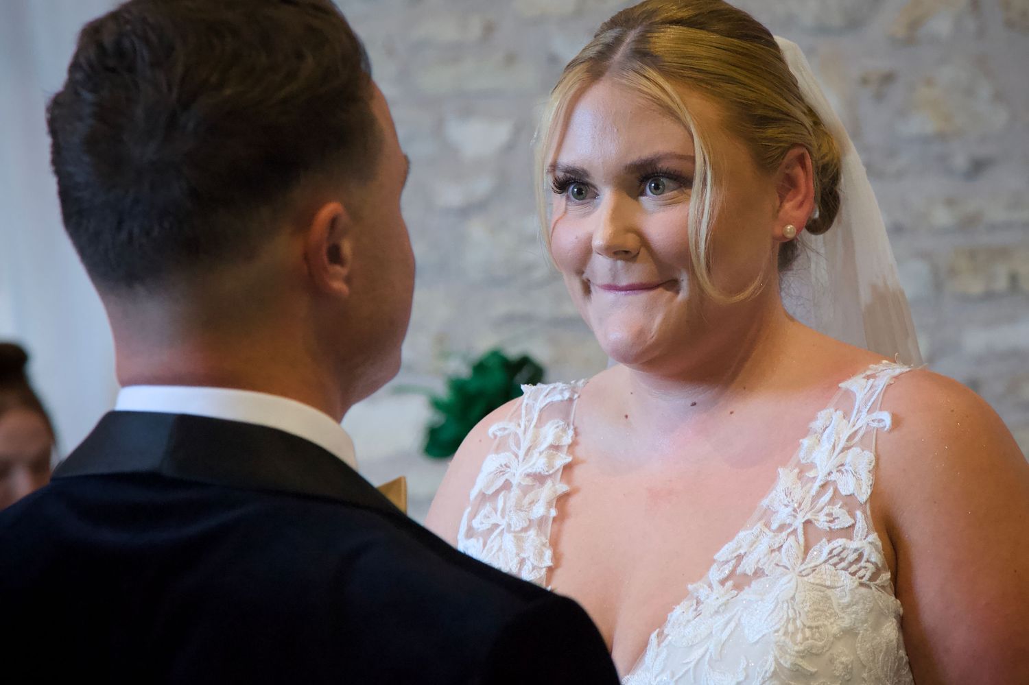 Couple sharing a joyful moment during their first dance at a rustic stone-walled wedding venue.