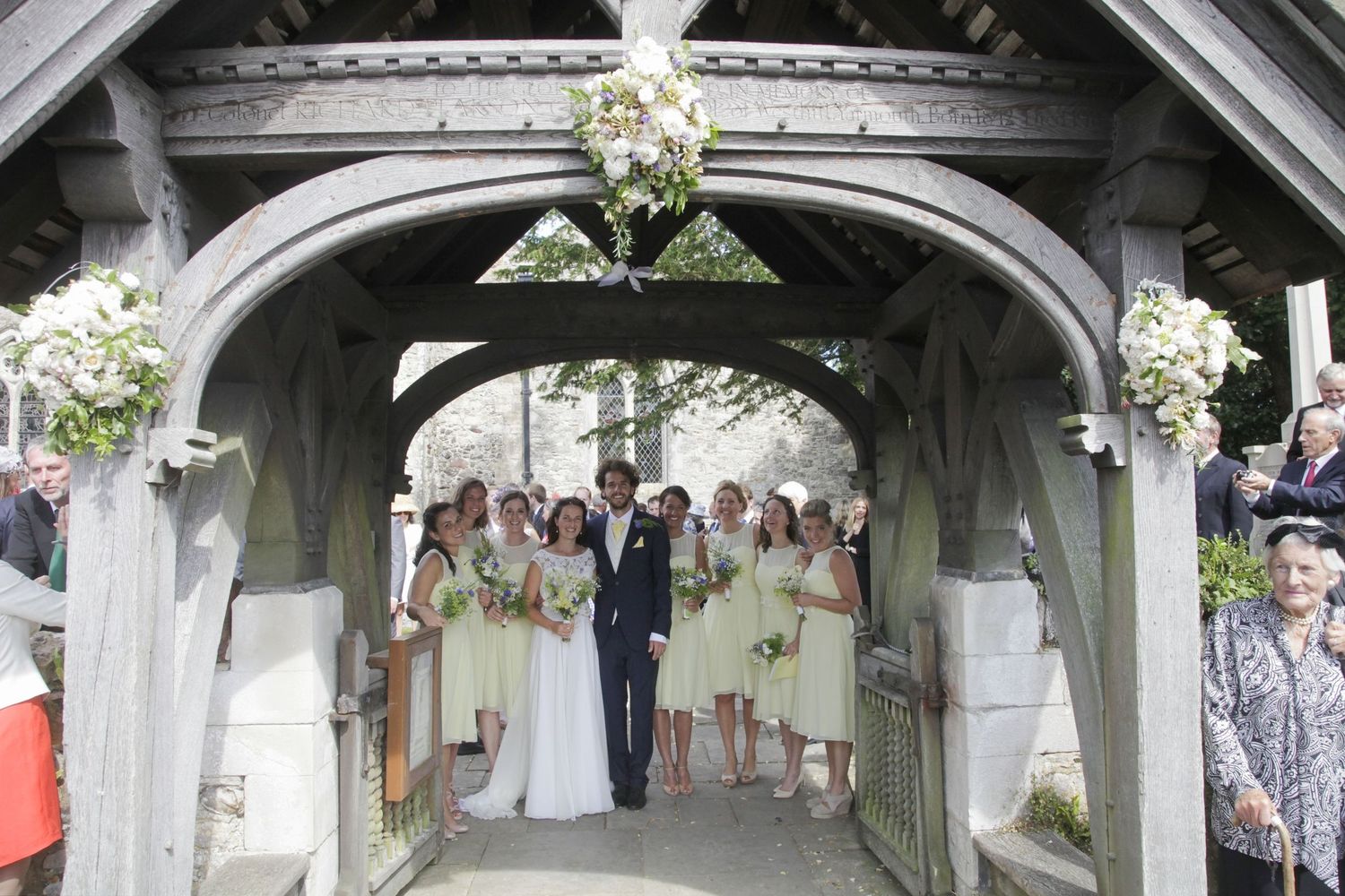 Decorated church entrance with white floral arrangements and wooden beams.