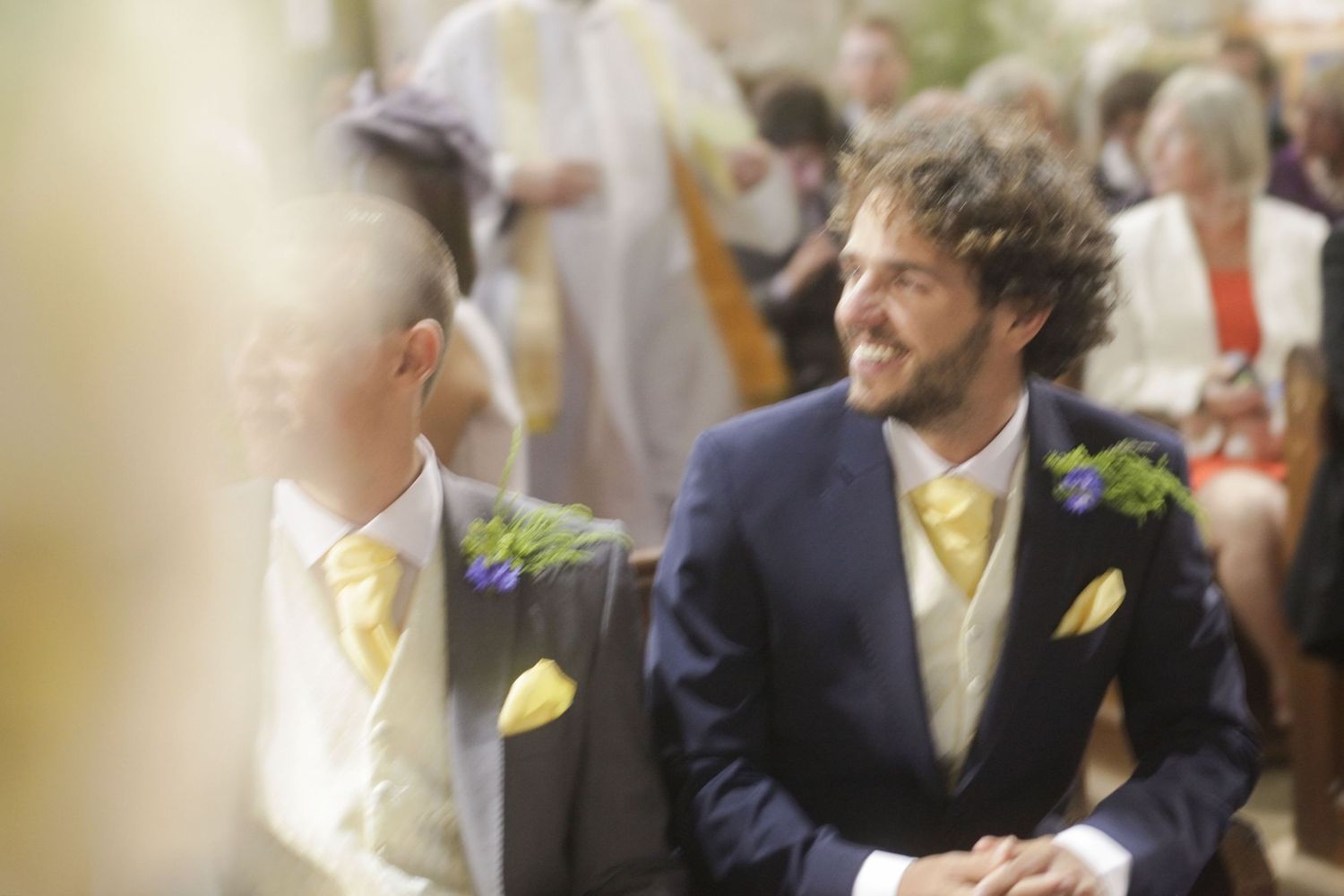 Elegant wedding ceremony taking place in a historic church with stained glass windows and stone archways.