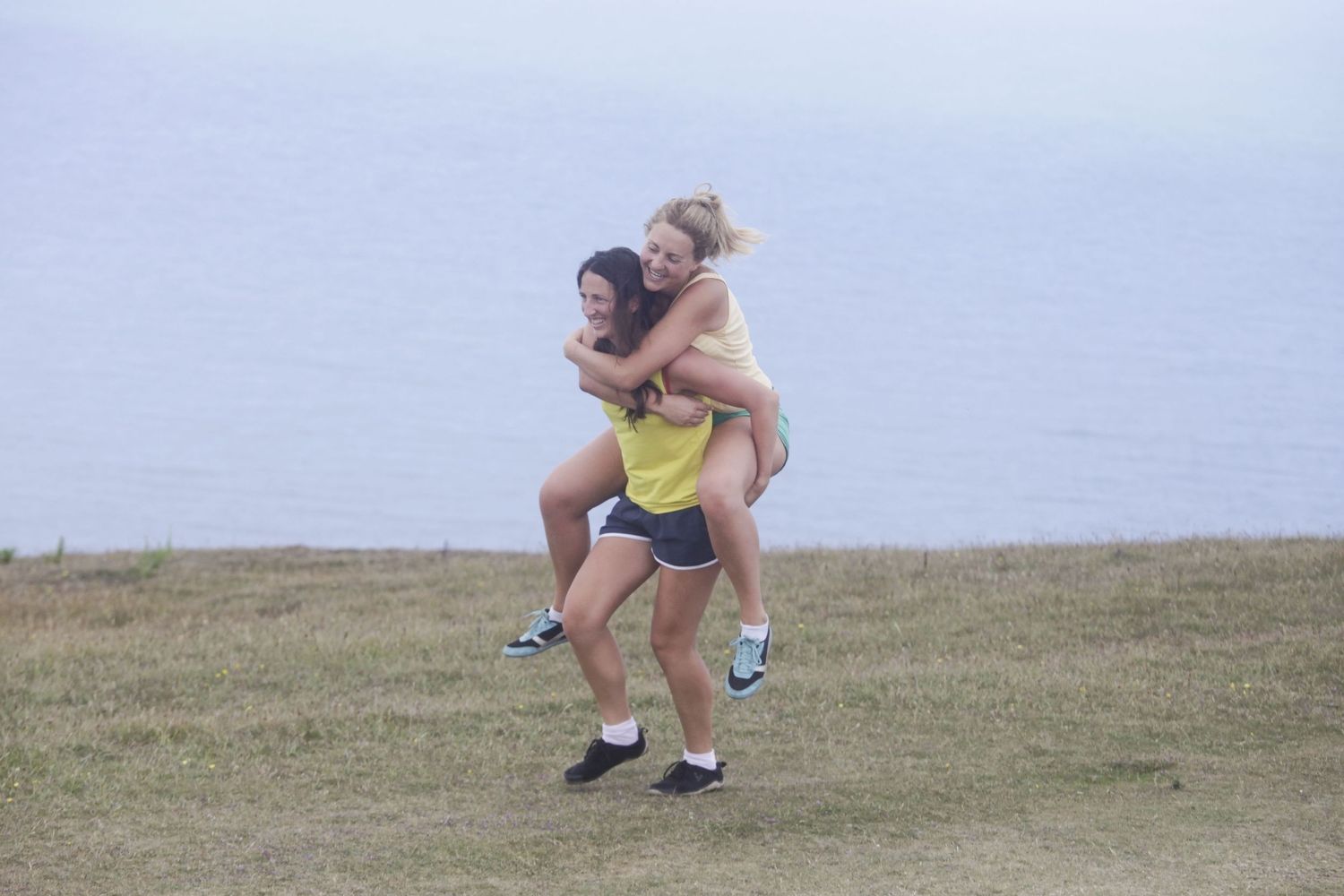 Group playing and posing on a grassy hilltop against cloudy sky.