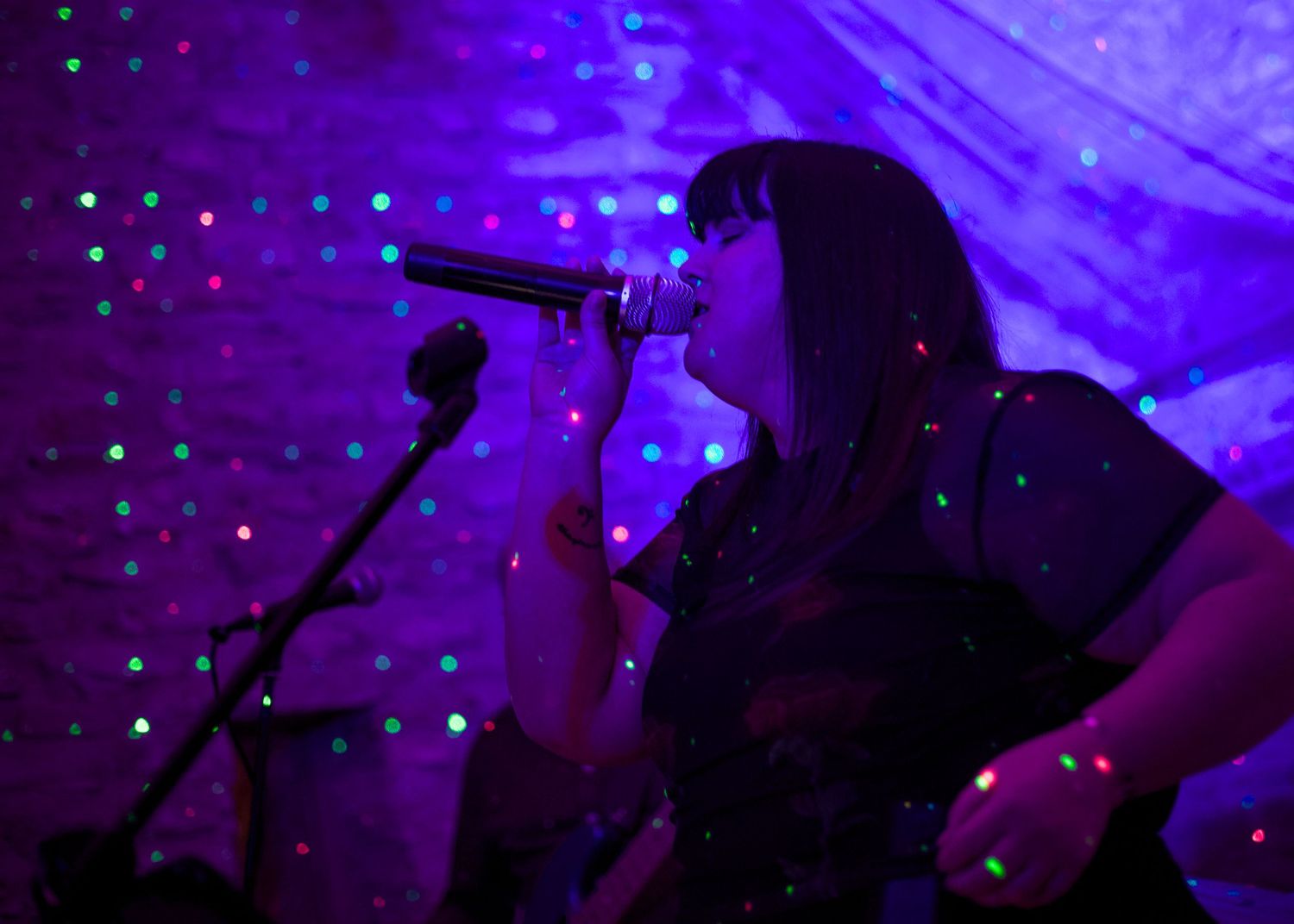 Band members of Freeze at Folly Farm Somerset wedding silhouetted against purple stage lighting during a performance.