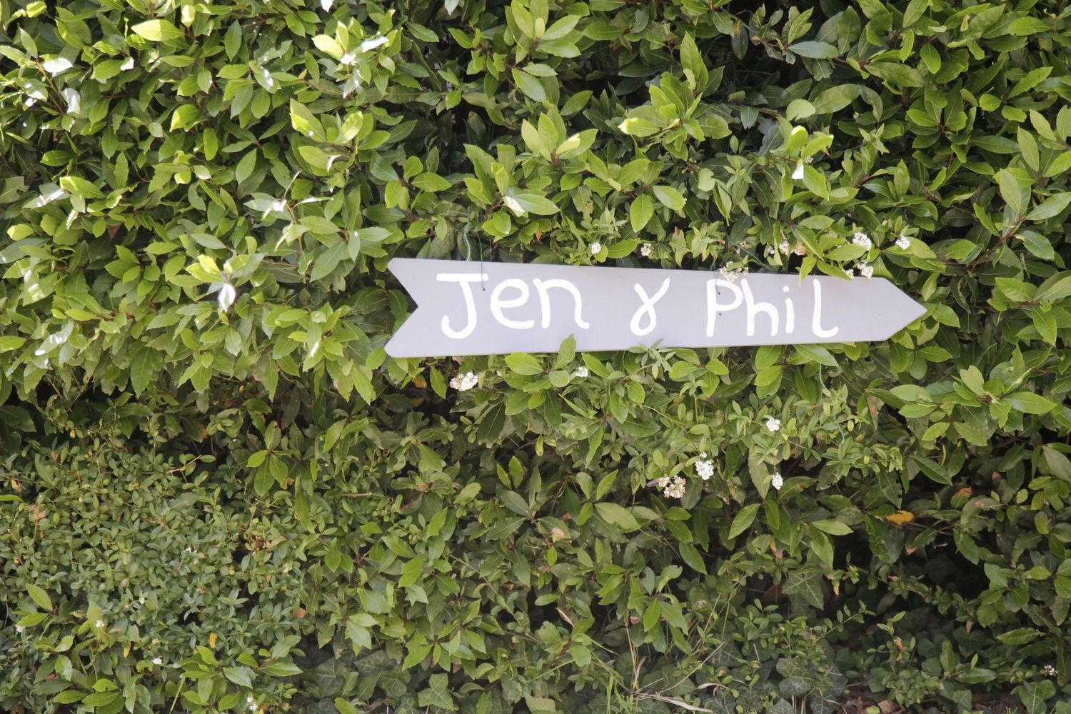Decorative garden sign with text among green leafy bushes.