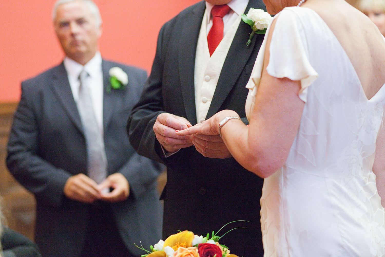 Bride and groom share a tender embrace during their wedding ceremony with sunflowers decorating the venue.