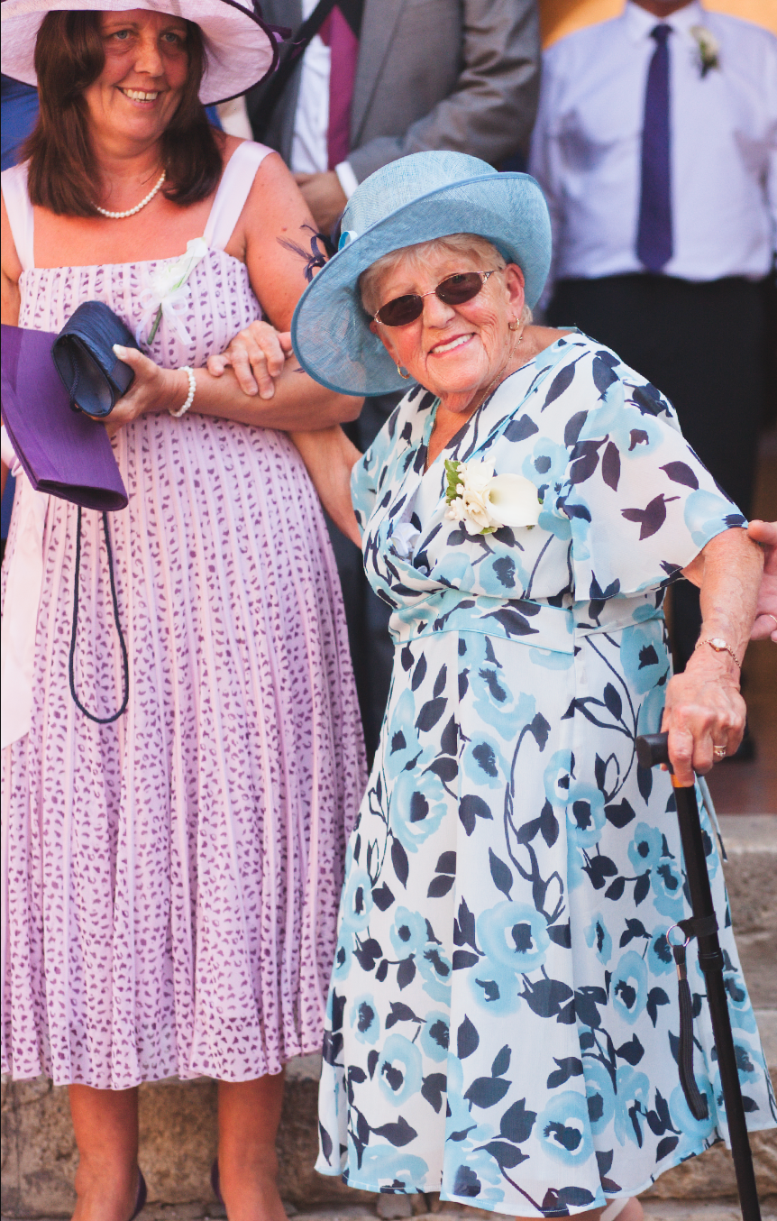 Wedding guests in summer attire mingle during an outdoor celebration.