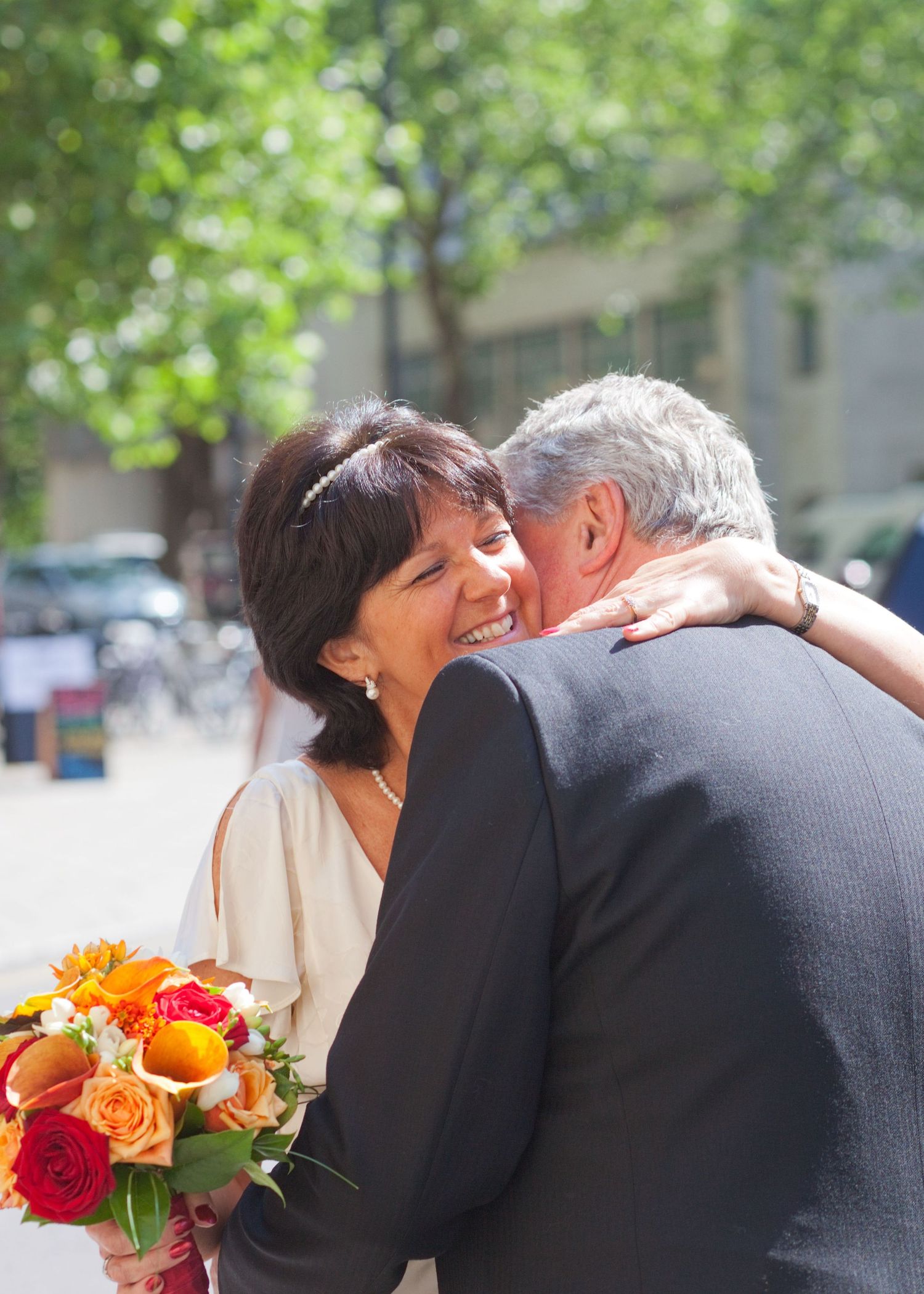 Happy couple sharing an intimate moment outdoors with colorful bouquet and formal attire.