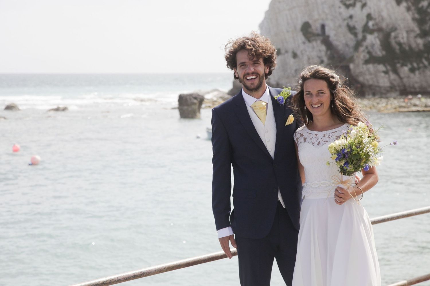 Newlyweds share a romantic moment by the seaside with white cliffs in the background.