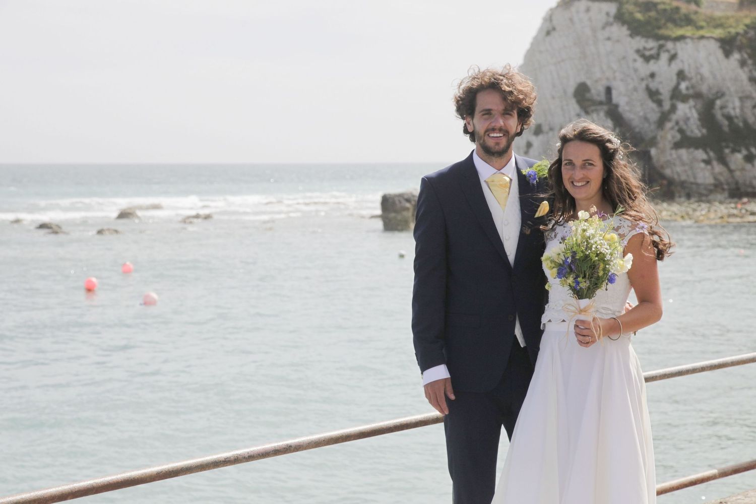 Wedding photography session along a coastal walkway with white cliffs and ocean backdrop.