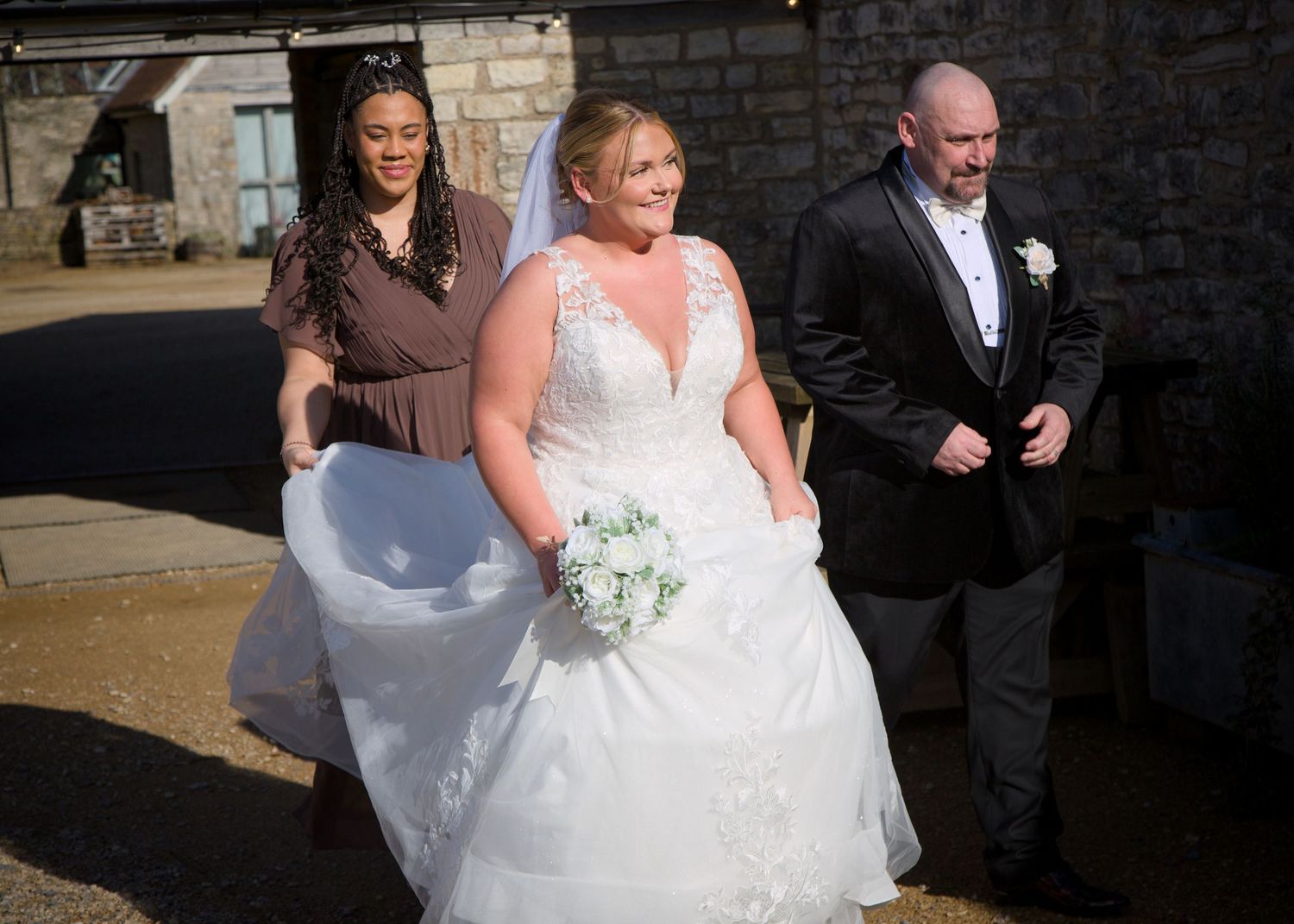Wedding party walking outside a brick building in formal attire.