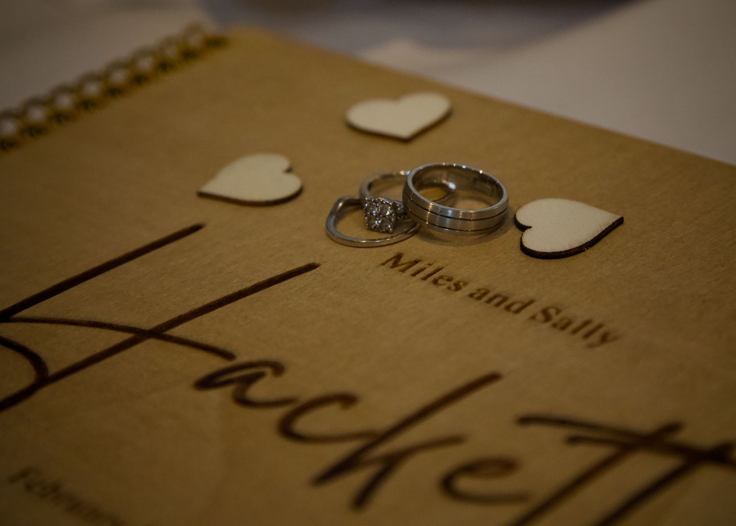 Wedding rings and decorative hearts arranged on vintage paper with text.
