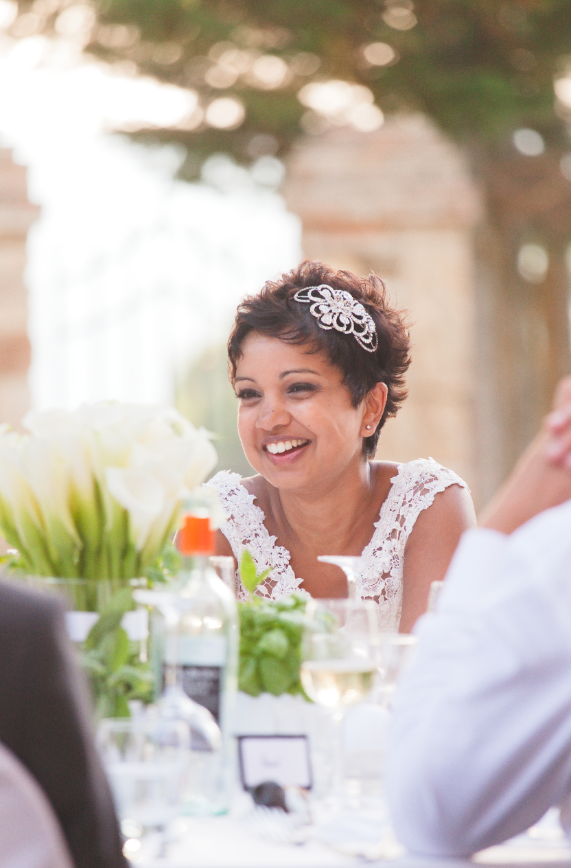 Bride in lace dress laughing joyfully during wedding reception dinner.