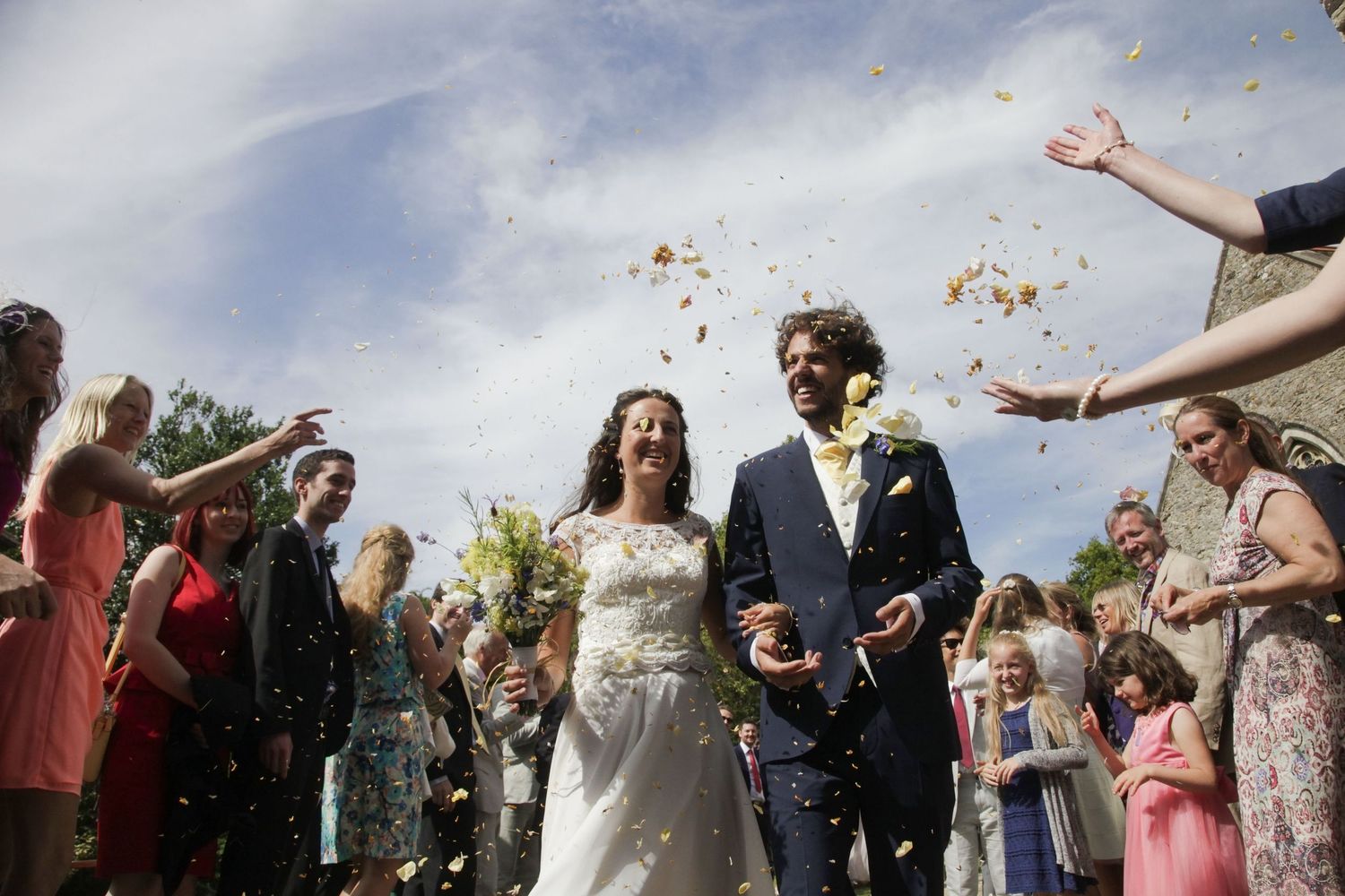 Festive outdoor wedding scene with confetti being tossed by guests.