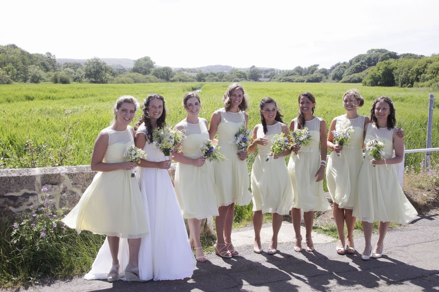 Wedding party members in coordinated attire gather for photos on a winding outdoor path.