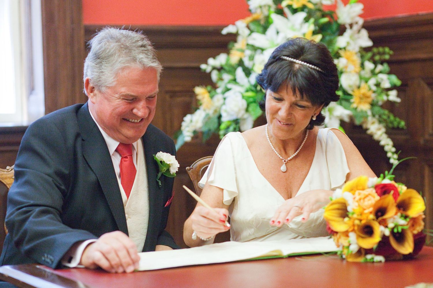 Wedding ceremony with sunflower decorations and couple signing documents at wooden table.
