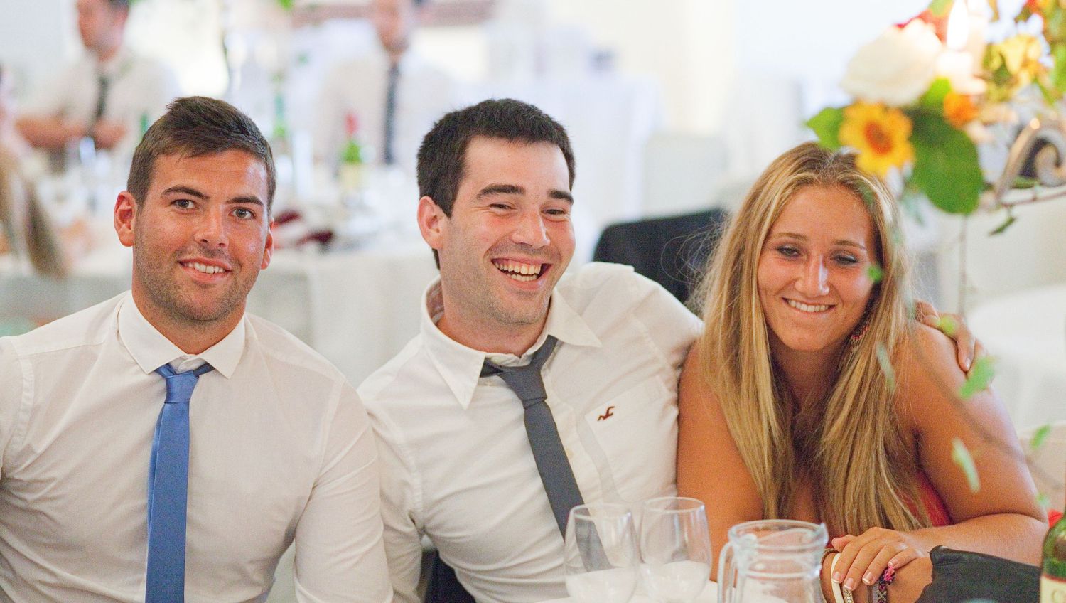 Wedding guests socializing and laughing at reception tables.