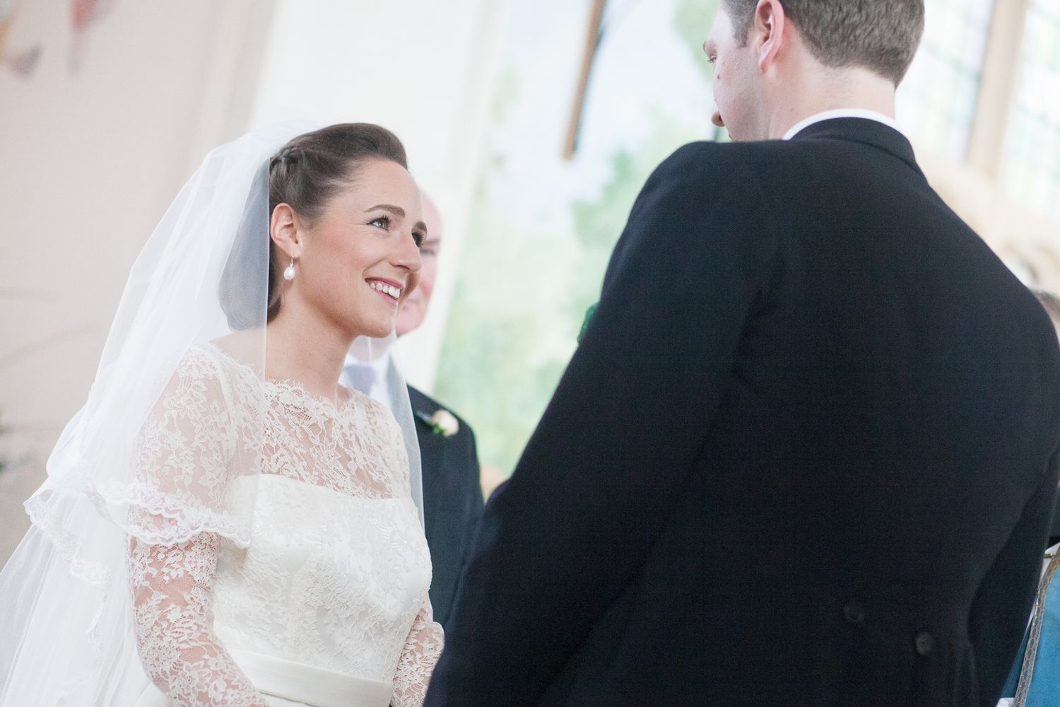 Bride and groom share joyful moment during indoor wedding ceremony.
