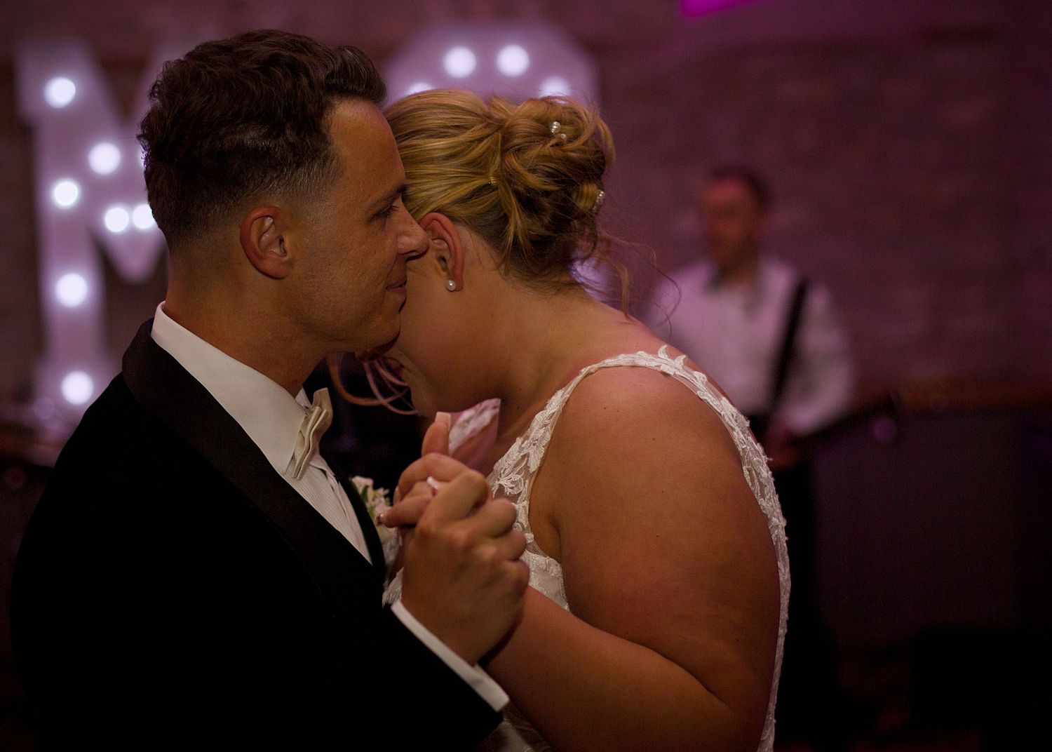 Couple shares their first dance under purple mood lighting at their wedding reception.