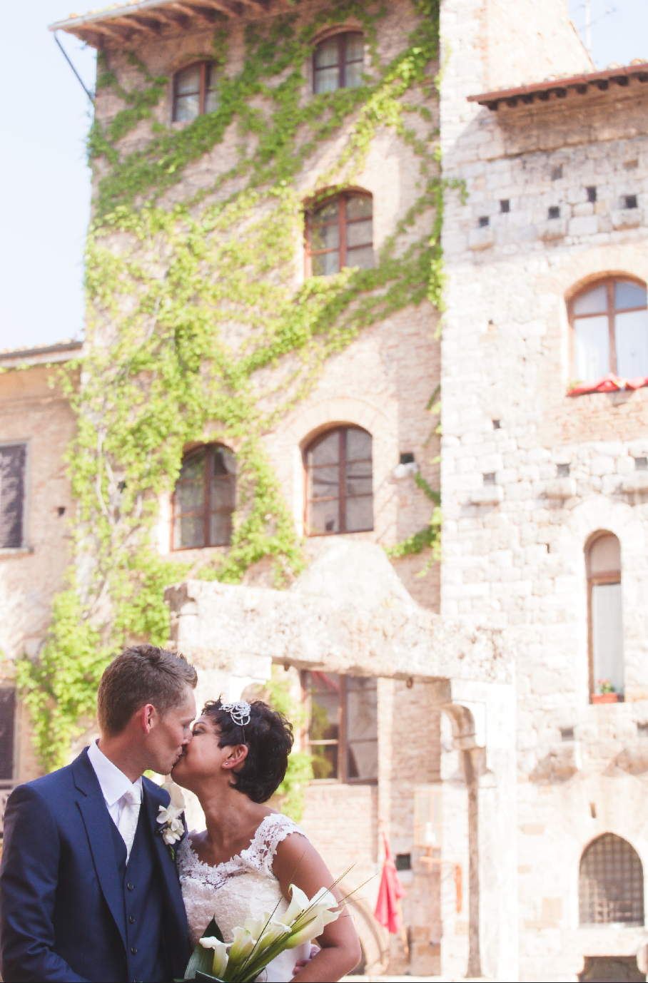 Romantic kiss captured during wedding photoshoot at historic stone building.
