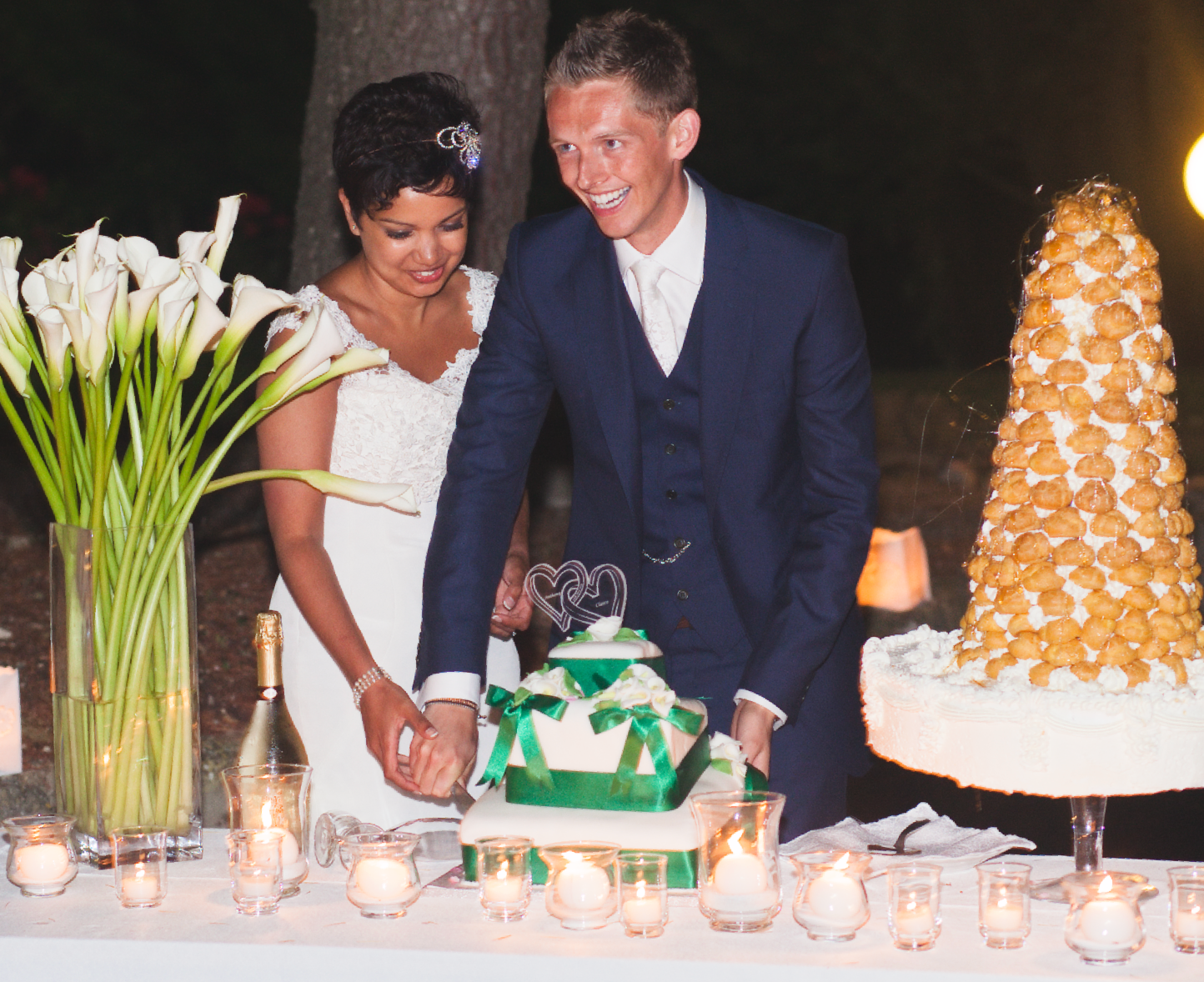 Wedding dessert table featuring multiple tiered cakes and candlelight decor.