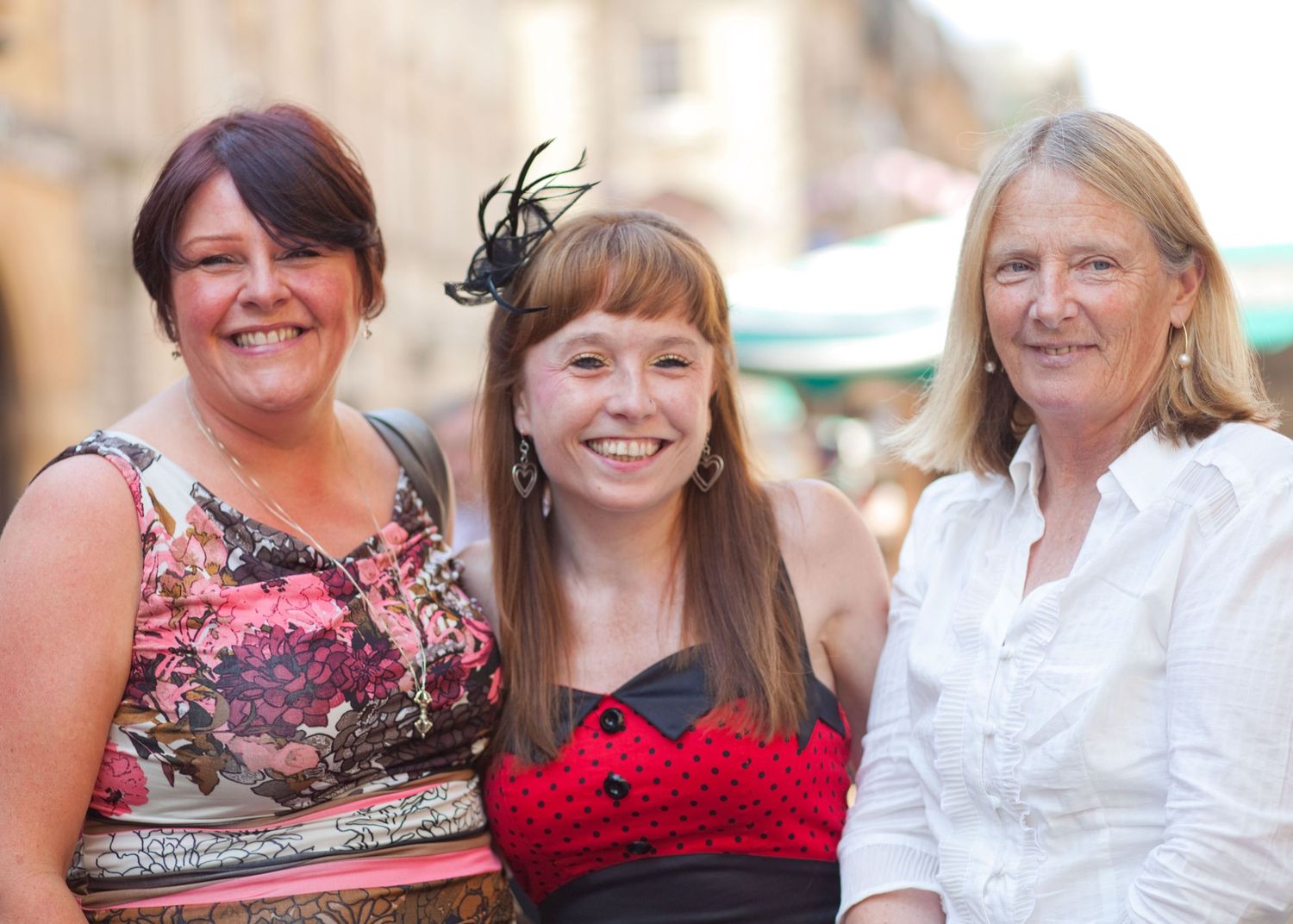 Wedding guests in colorful dresses smiling and celebrating at an outdoor reception.