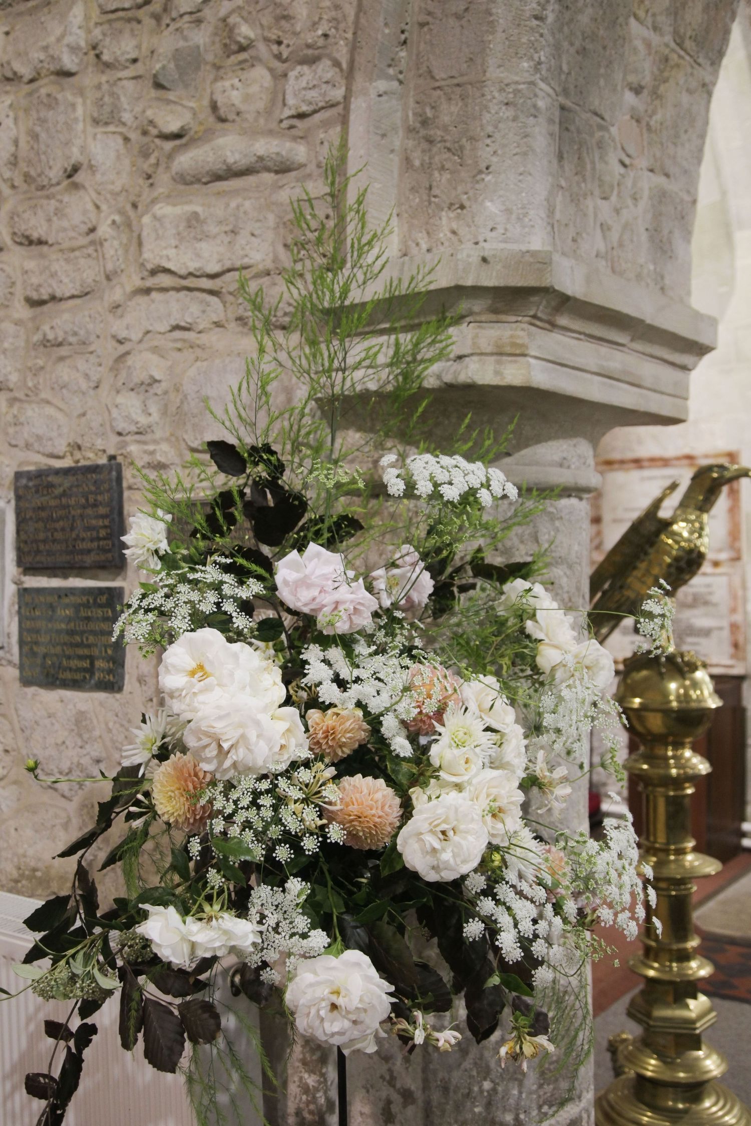 Elegant white and peach floral arrangements adorning a stone church interior.