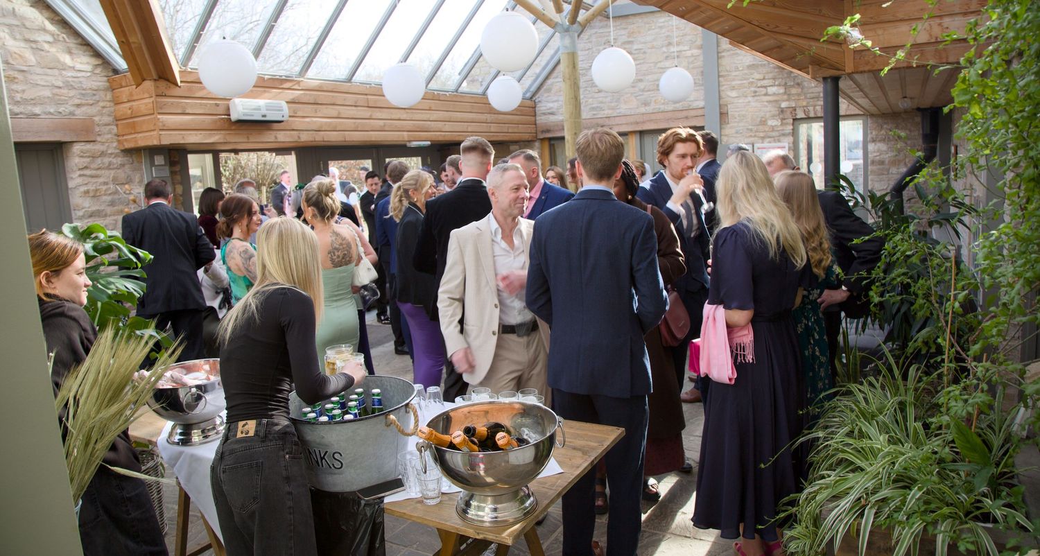 Indoor wedding reception at Folly Farm Somerset wedding venue with natural skylight and greenery decorations.
