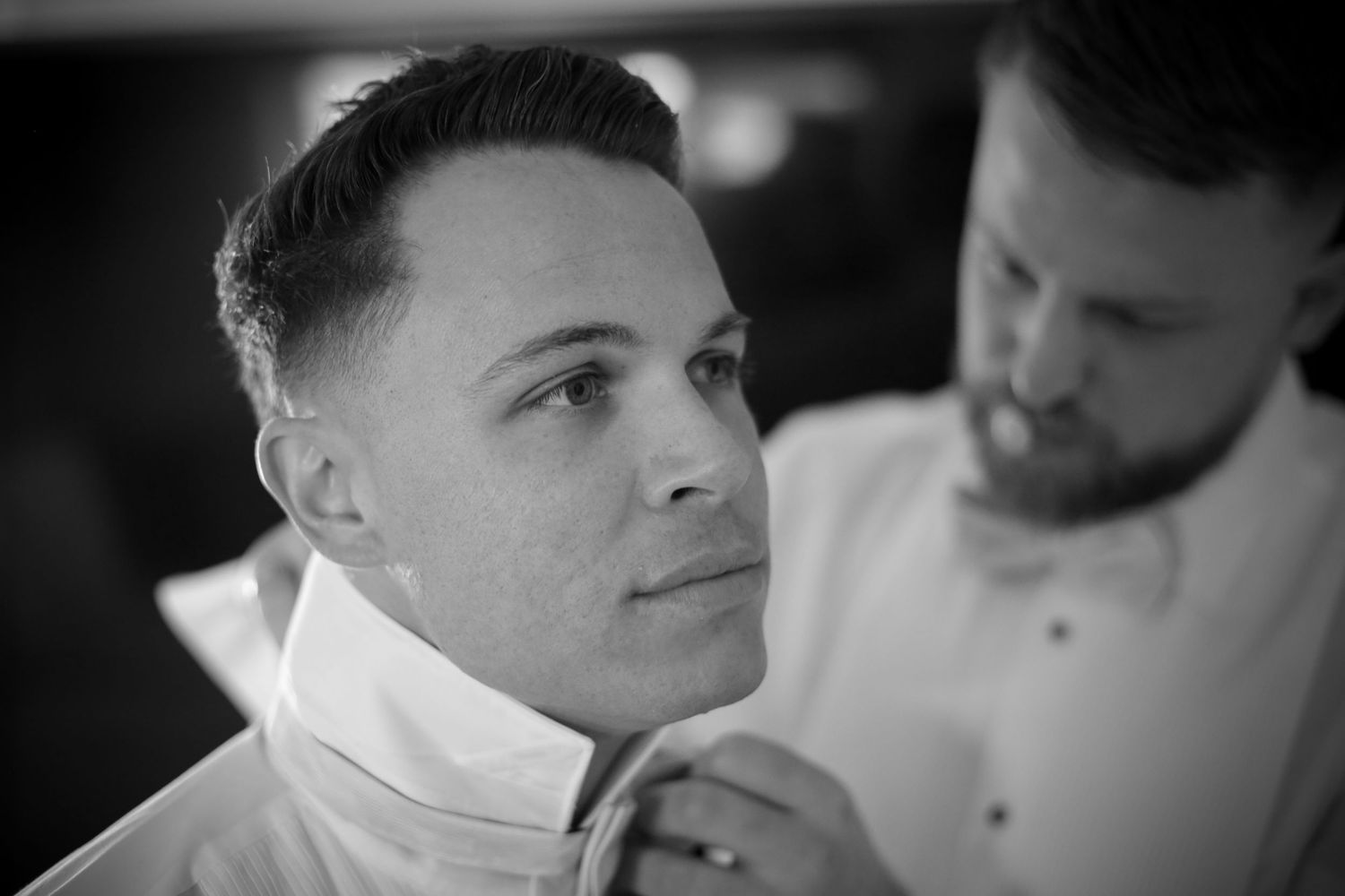 A black and white portrait of a groom getting ready on his wedding day.