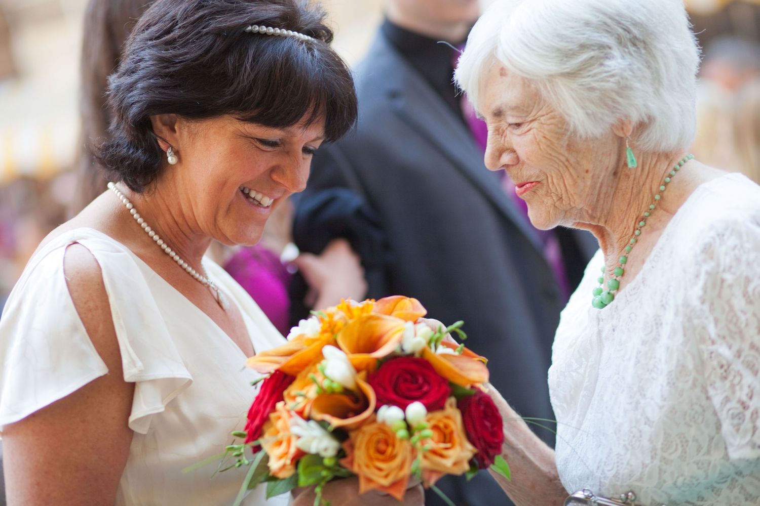 Wedding attendees share joyful moments with bright floral bouquets.