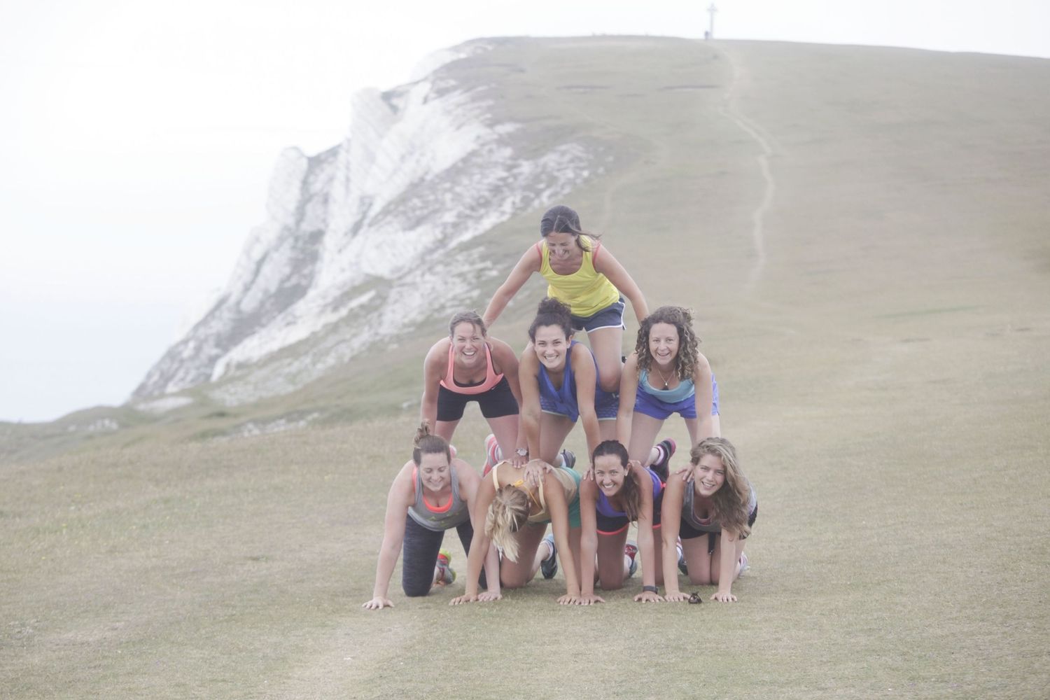 People posing together on a grassy hillside overlooking white chalk cliffs and ocean.